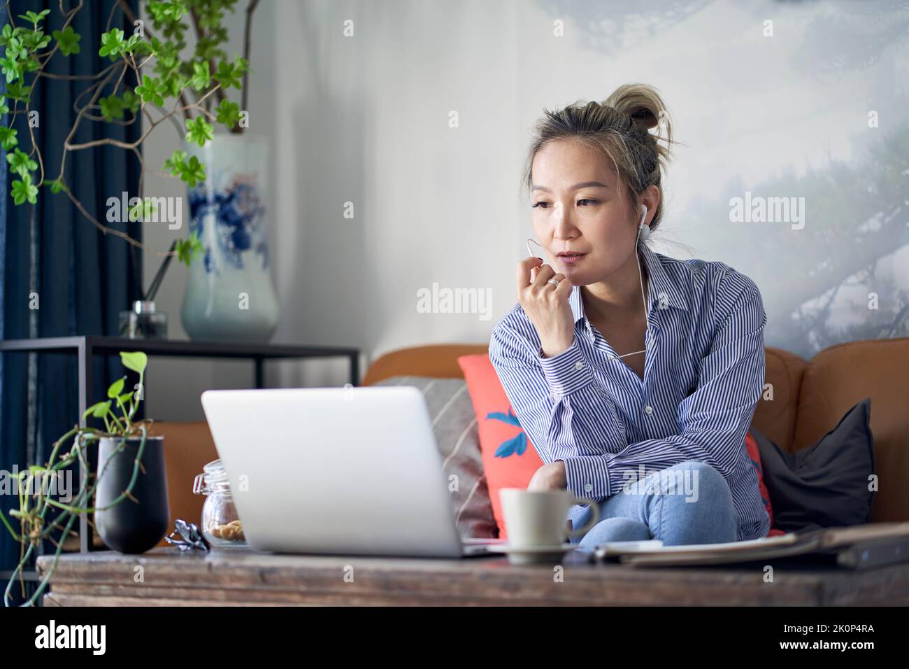 donna d'affari asiatica professionista che lavora da casa video chattare utilizzando il cellulare e il computer portatile Foto Stock