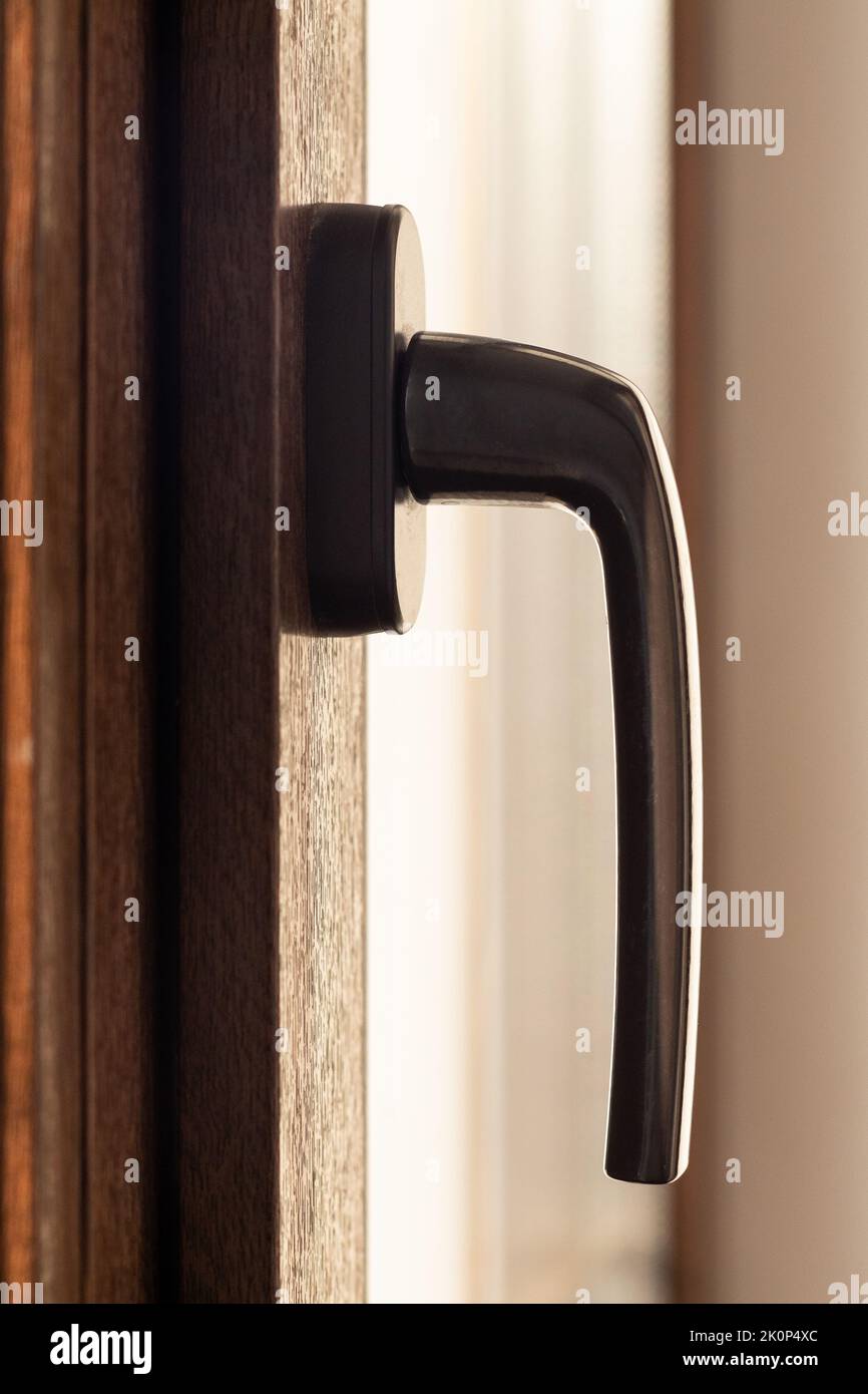 Maniglia per finestra su una finestra marrone in metallo-plastica, vista laterale, verticale Foto Stock