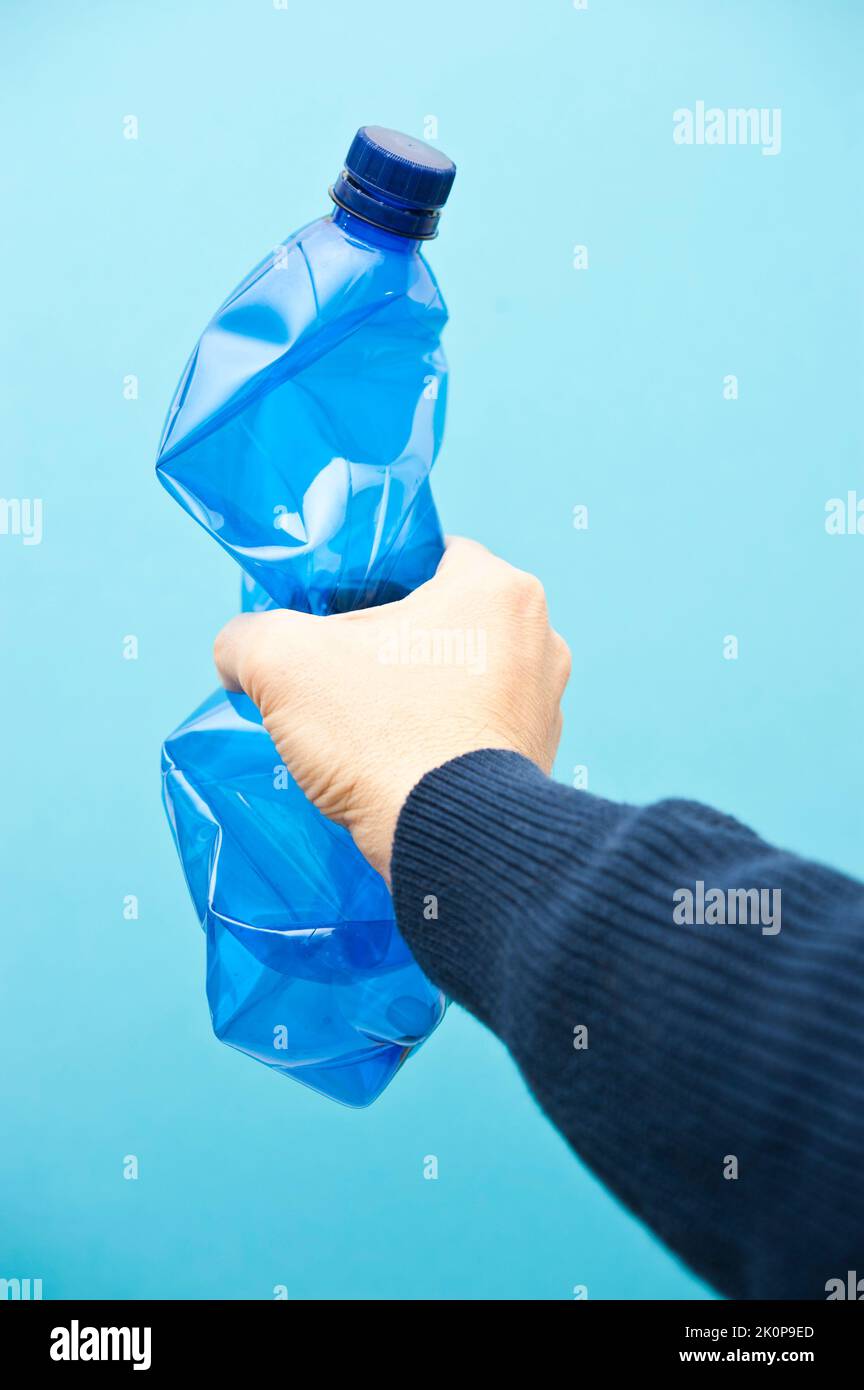 mano che tiene una bottiglia di plastica blu, concetto di riciclaggio Foto Stock