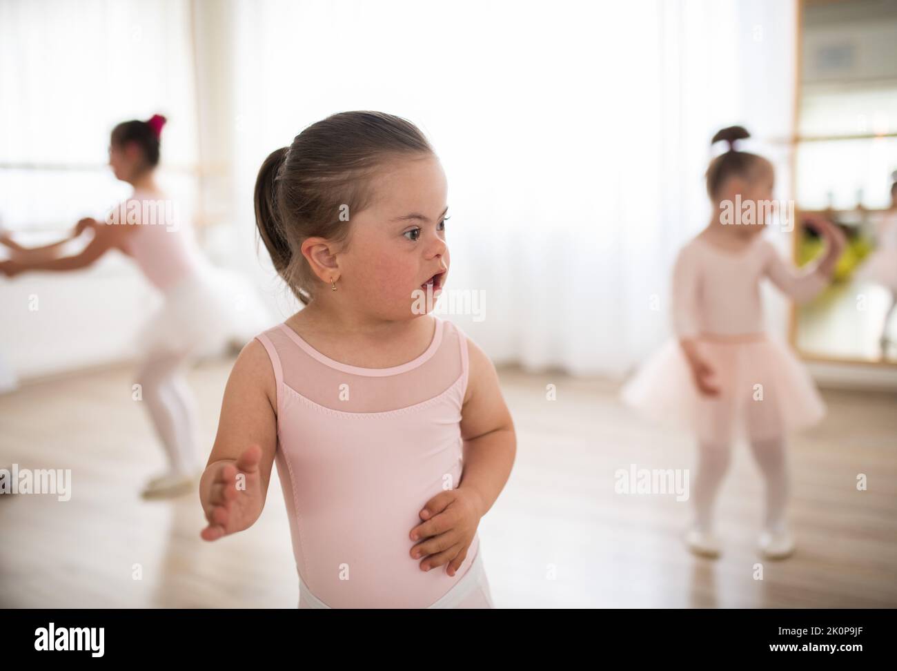 Bambina con sindrome di Down alla lezione di balletto in studio di danza. Concetto di integrazione e di educazione dei bambini disabili. Foto Stock