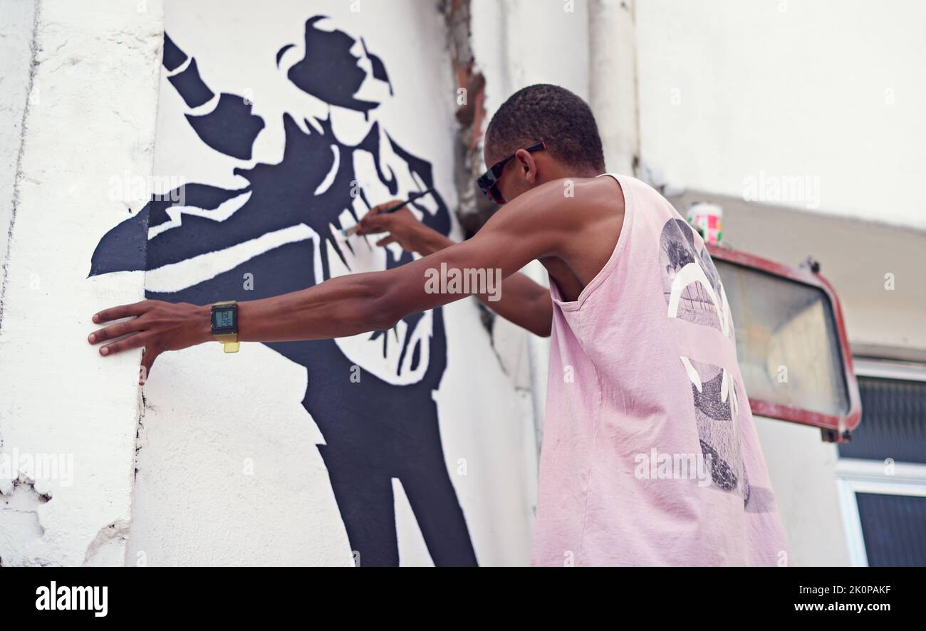 Espressione creativa. Un giovane graffiti che dipinge un disegno su una parete. Foto Stock