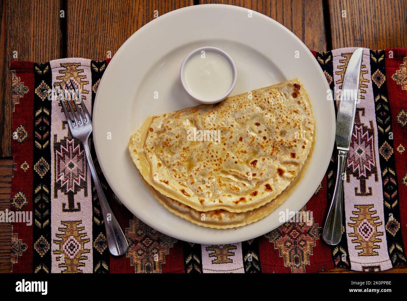 Yantyki con agnello fritto in una padella asciutta e ingrassato con burro con panna acida su un tovagliolo in ceramica, con un tovagliolo sullo sfondo. Superiore Foto Stock
