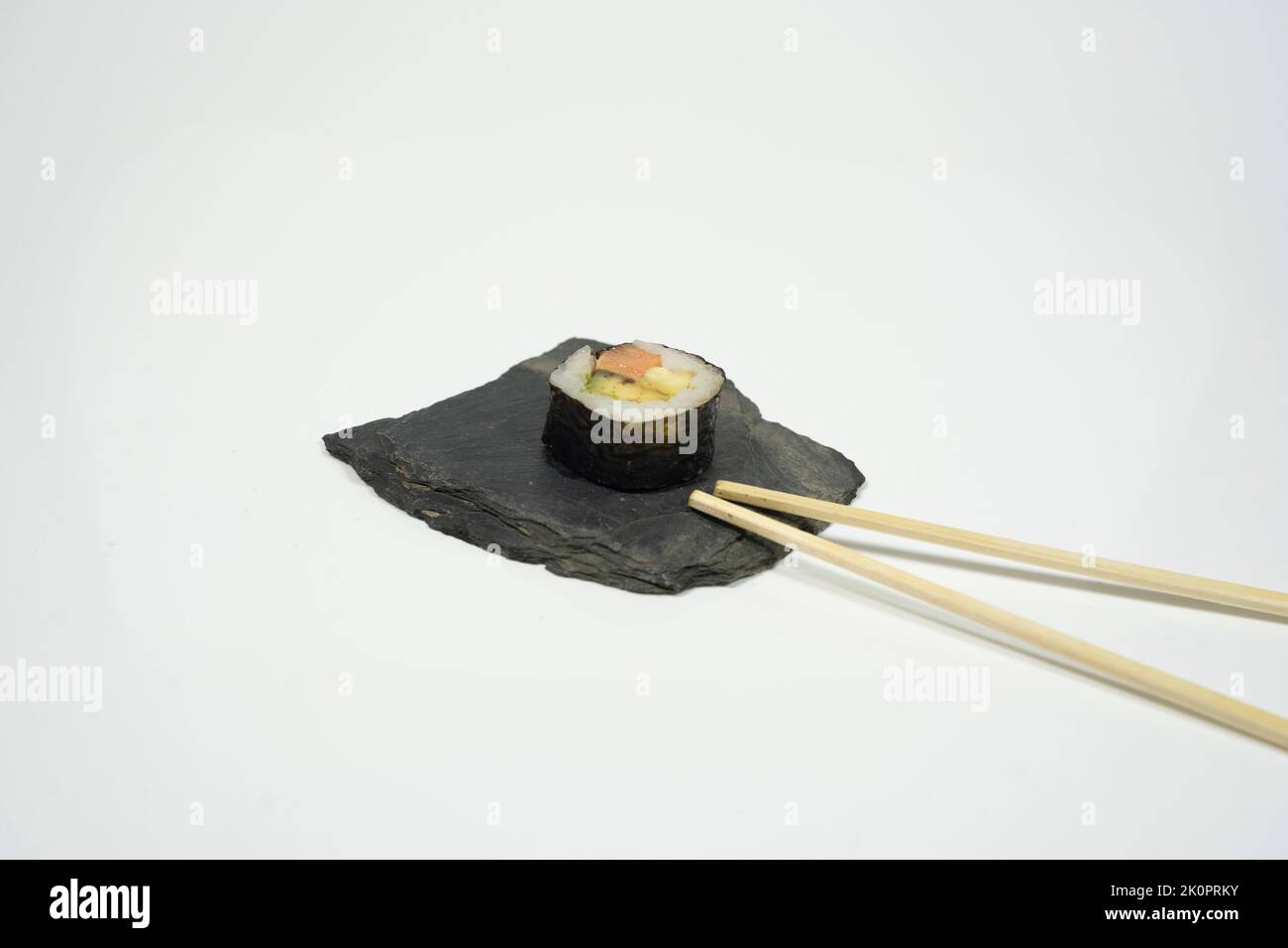 un pezzo di shushi con bacchette su sfondo bianco Foto Stock