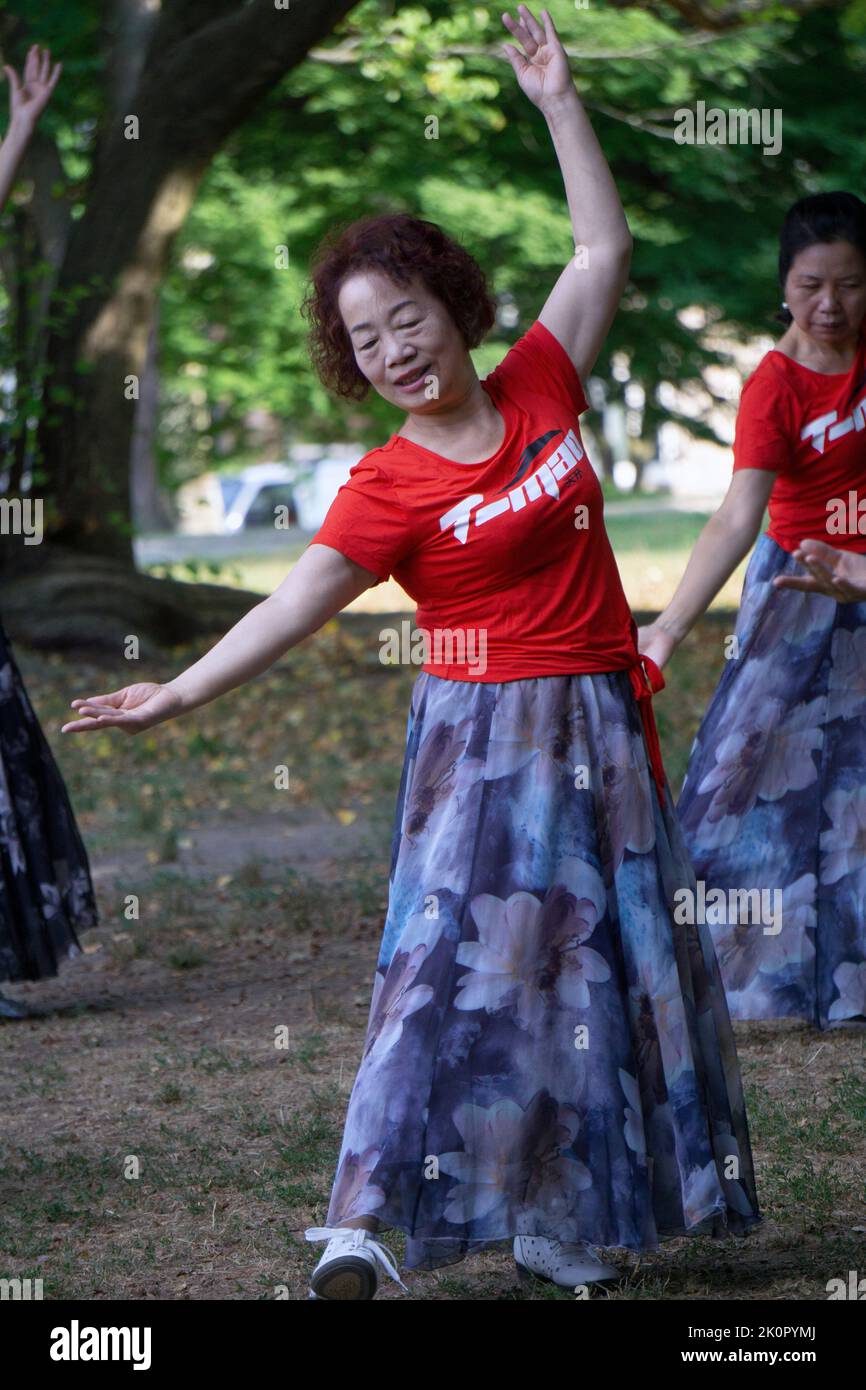 Una donna cinese americana ad una lezione di danza e ginnastica yuanji in un parco a Queens, NYC. È una tradizione cinese del mattino. Foto Stock