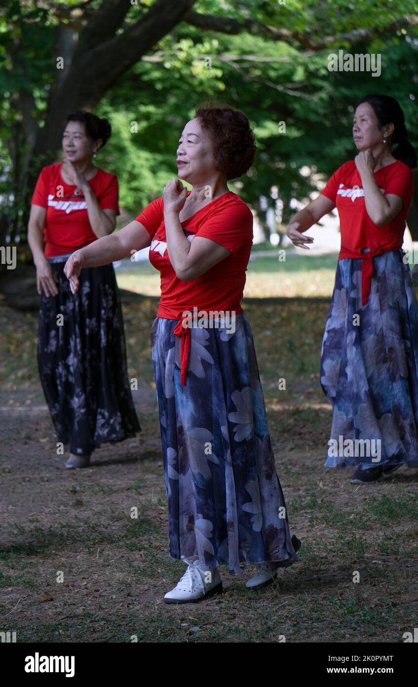 Una donna cinese americana ad una lezione di danza e ginnastica yuanji in un parco a Queens, NYC. È una tradizione cinese del mattino. Foto Stock