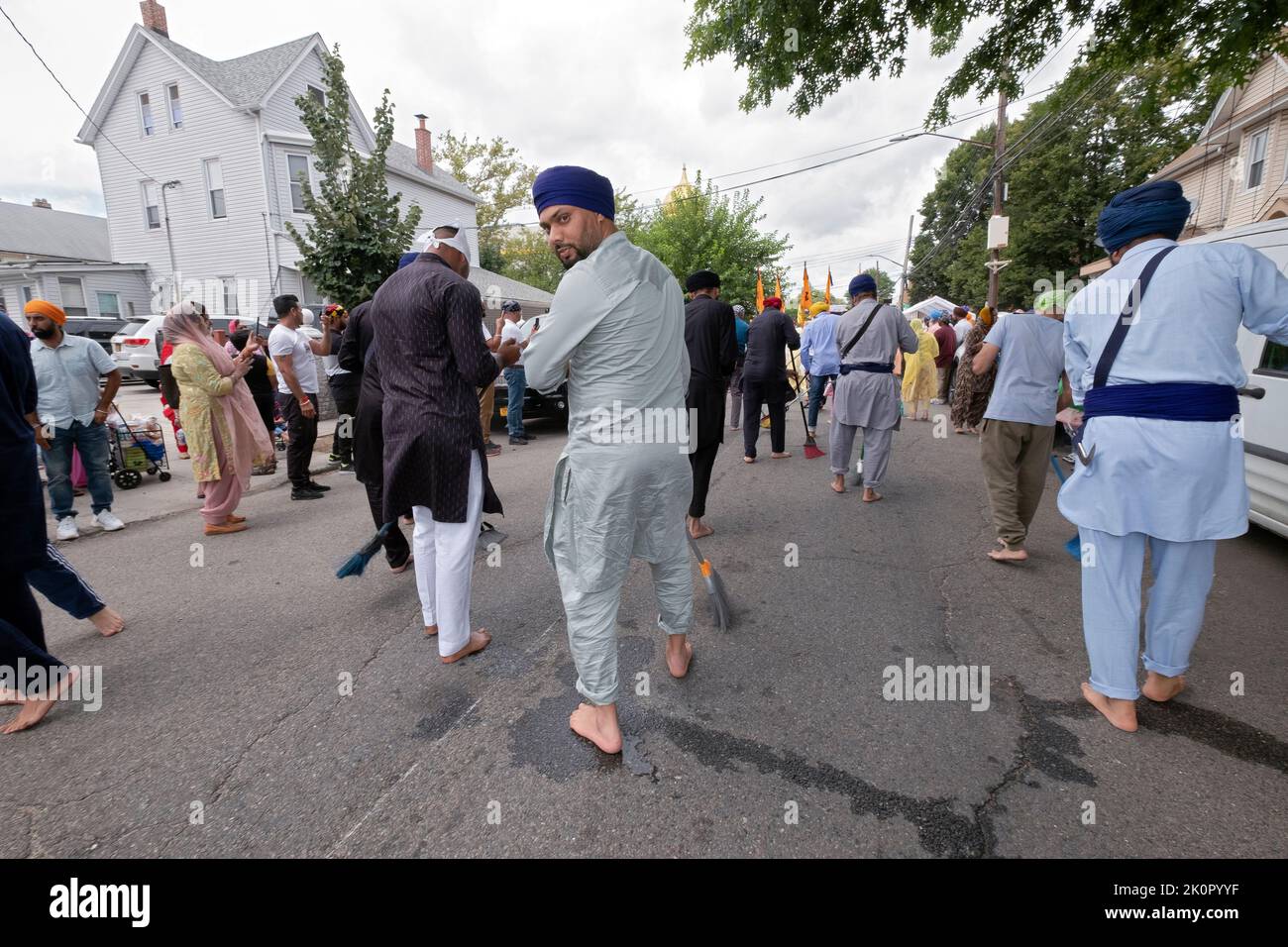 Devout Sikh uomini e donne spazzano 118th strada dove una parata galleggiante che porta il loro libro santo, Guru Granth Sahib, passerà. Alla Parata Nagar Kirtan. Foto Stock