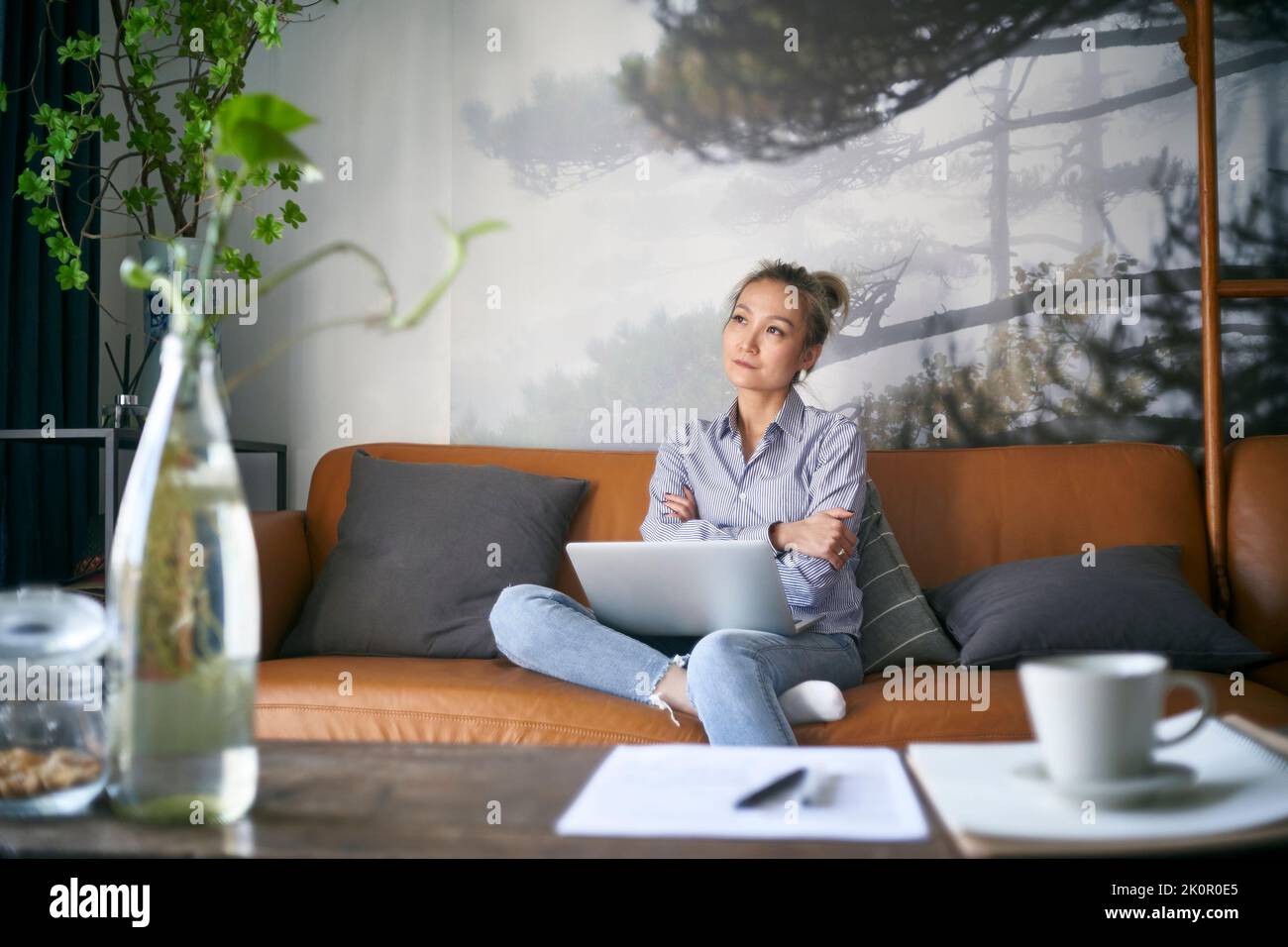 donna asiatica d'affari matura e professionale che contempla mentre lavora da casa utilizzando un computer portatile Foto Stock