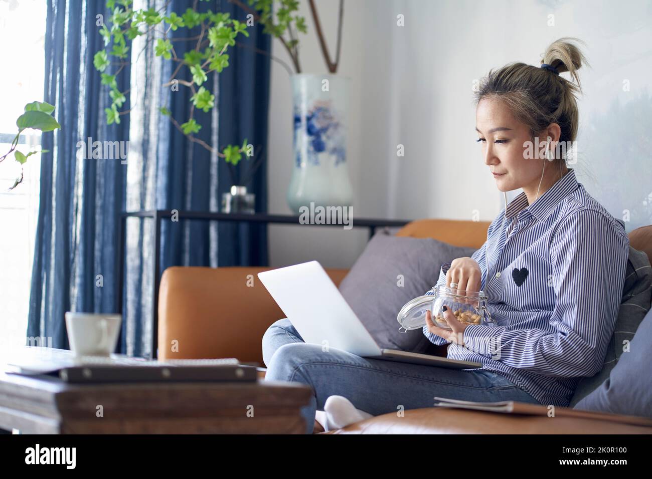donna asiatica matura e professionale che lavora da casa utilizzando un computer portatile vista laterale Foto Stock