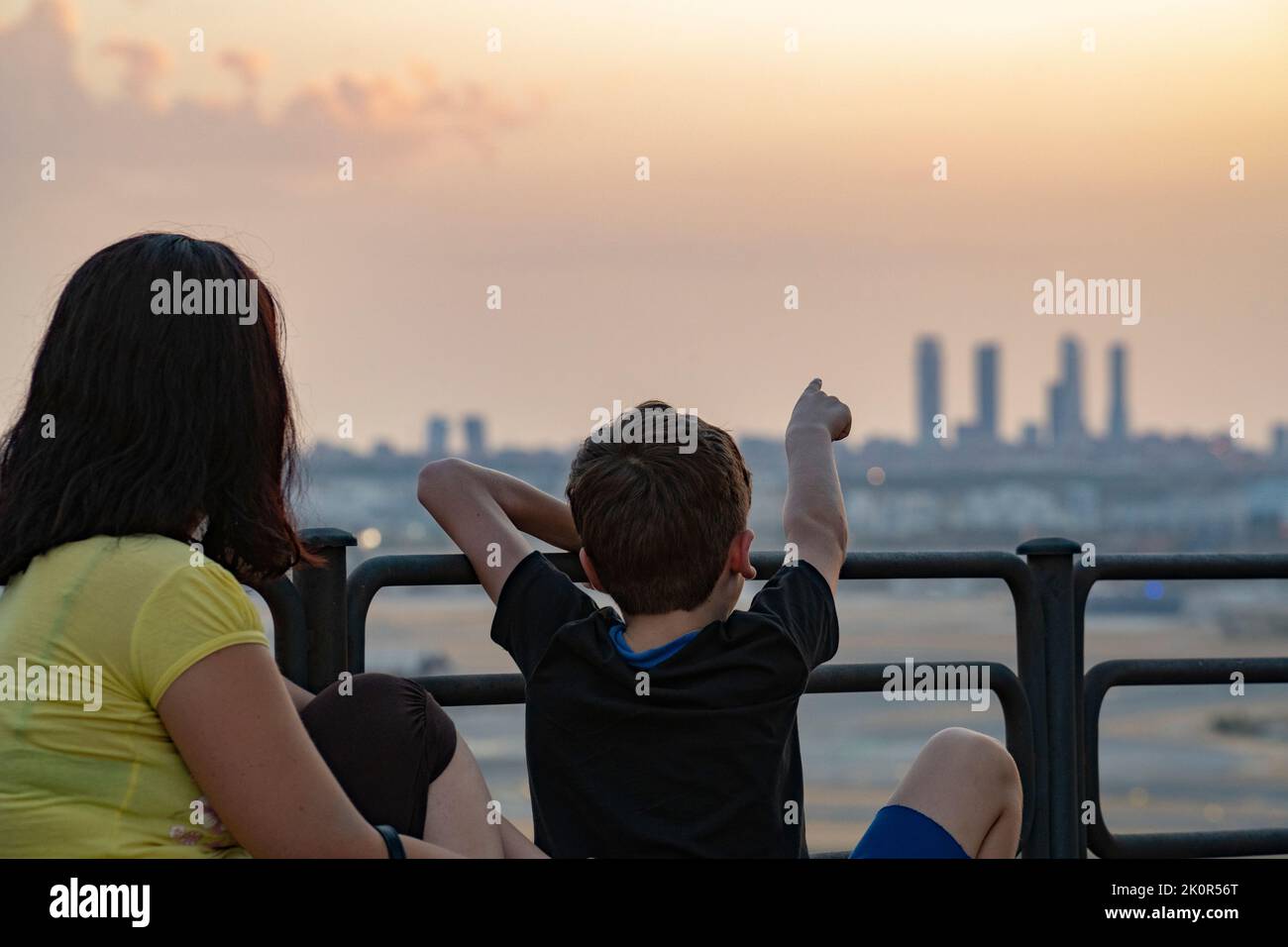 Mamma e bambino che guardano lo skyline di Madrid durante il tramonto.Kid che indica la silhouette delle 4 torri. Kio torri. Foto Stock