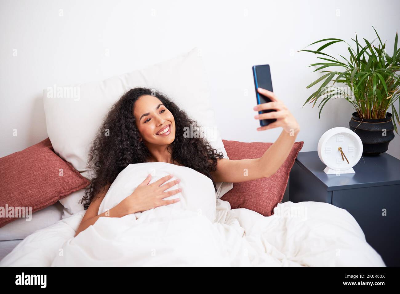 Un giovane influencer prende selfie mentre si sveglia a letto Foto Stock