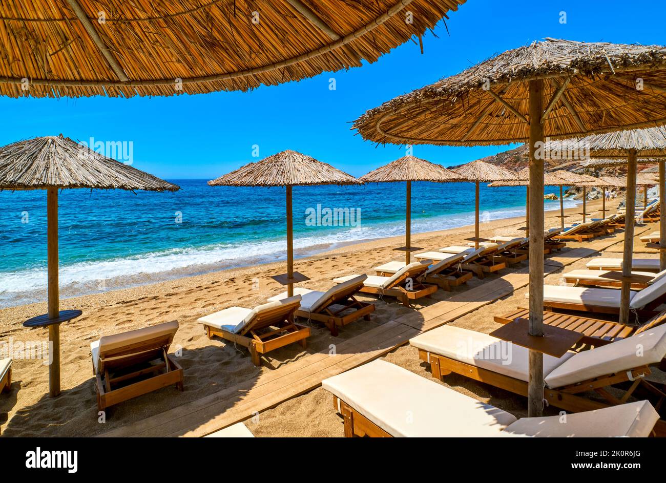 File di ombrelloni e lettini pronti per i turisti sulla spiaggia sabbiosa. Vacanze estive, solarium, nuoto, relax, cielo blu, mare, spiaggia Foto Stock