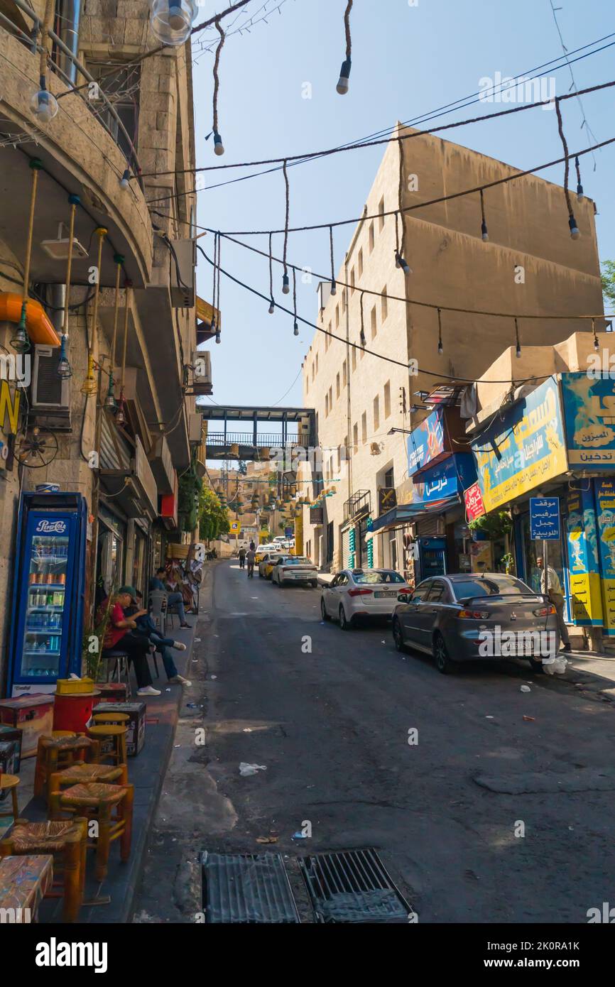 06.18.2022. Amman, Giordania. Una strada stretta locale ad Amman con piccoli mercati, persone e automobili. Foto di alta qualità Foto Stock