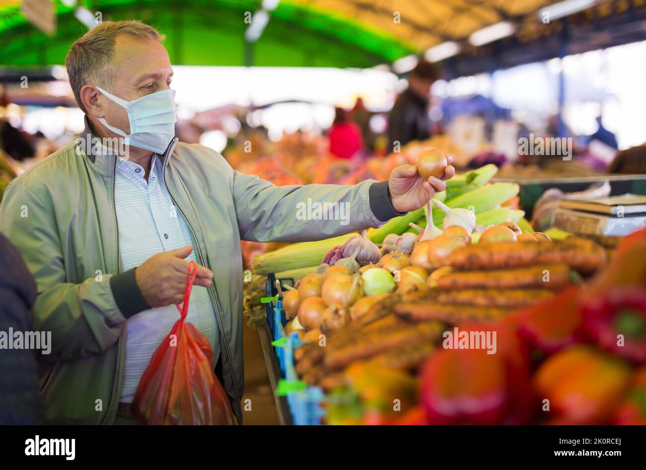 Uomo di mezza età in maschera di acquisto cipolle Foto Stock