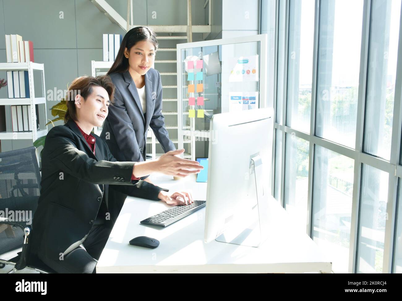Uomo e donna asiatica d'affari che guarda lo schermo del computer portatile per discutere e lavorare in ufficio Foto Stock