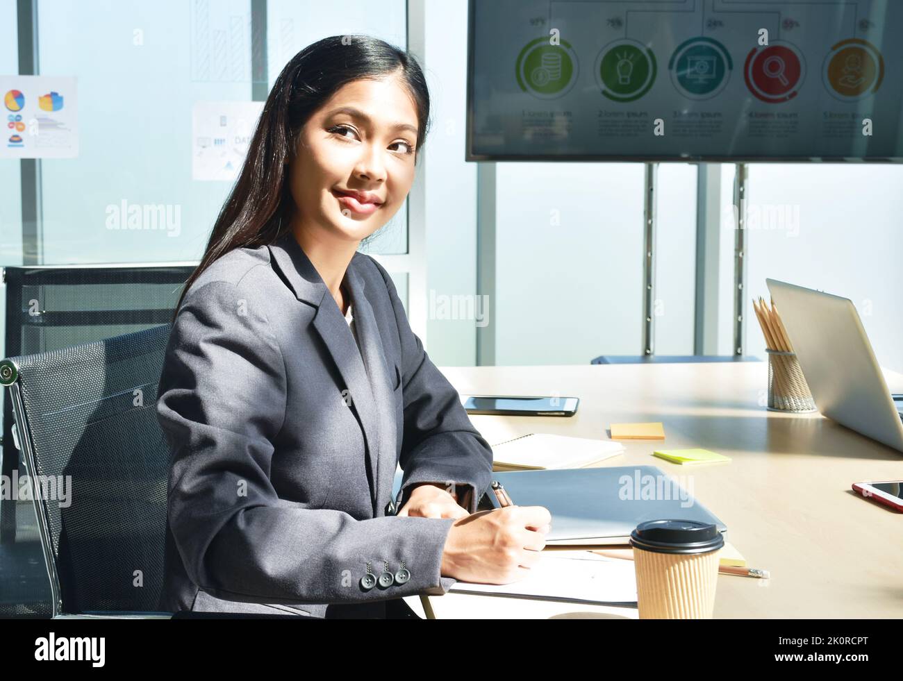 Felice donna asiatica d'affari nota sul libro e sul lavoro in ufficio Foto Stock