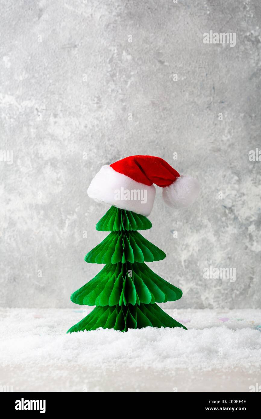 Albero di Natale di carta verde con l'arredamento rosso di festa del cappello di santa Foto Stock