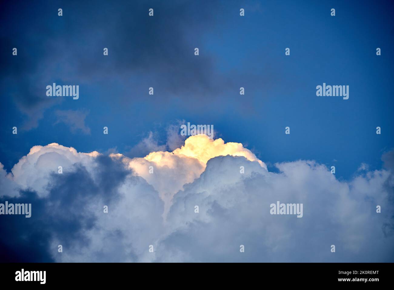 Cielo suggestivo con nuvole scure e una piccola luce che illumina una nuvola bianca Foto Stock