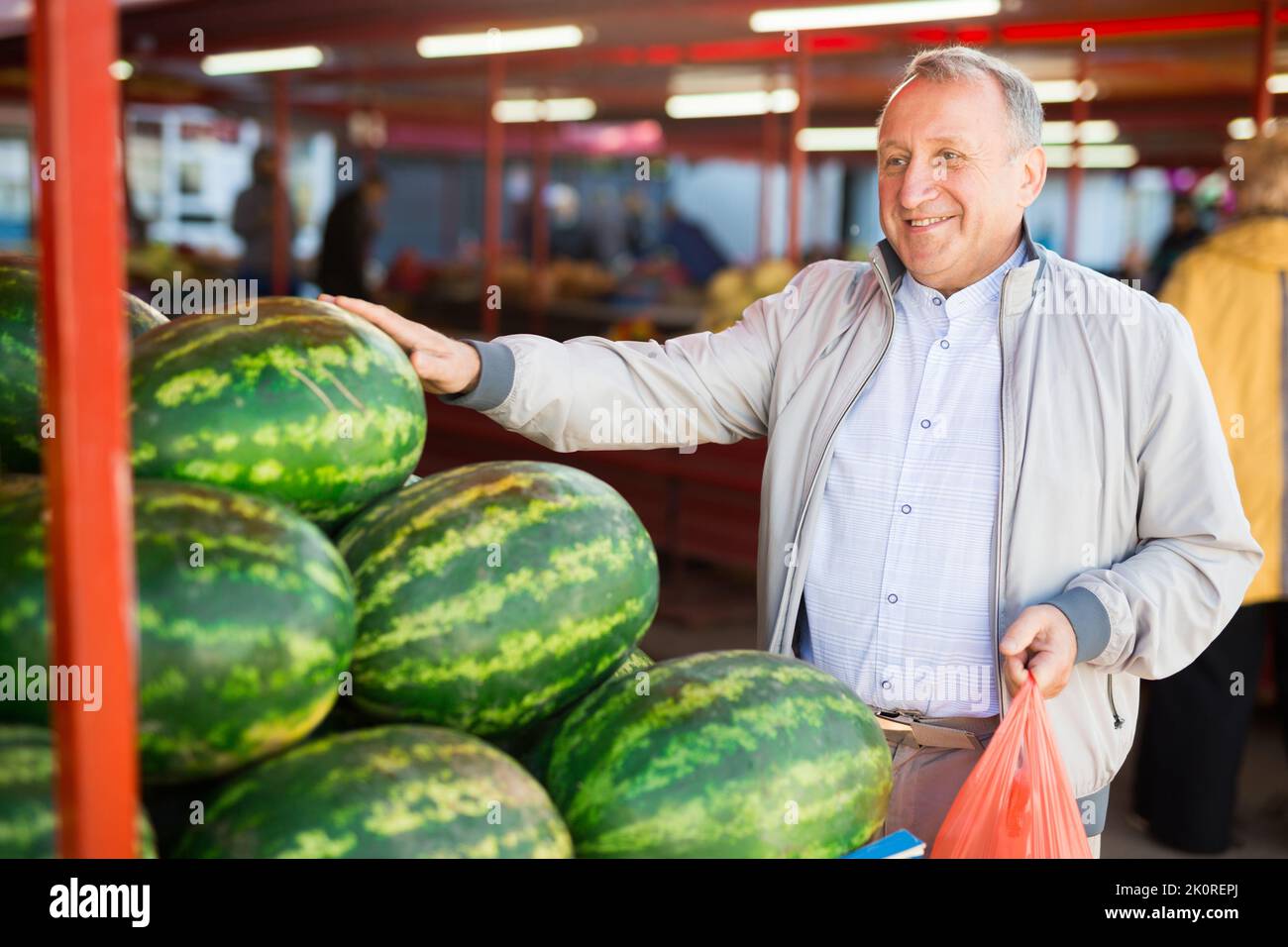 Uomo che sceglie anguria in negozio di frutta Foto Stock