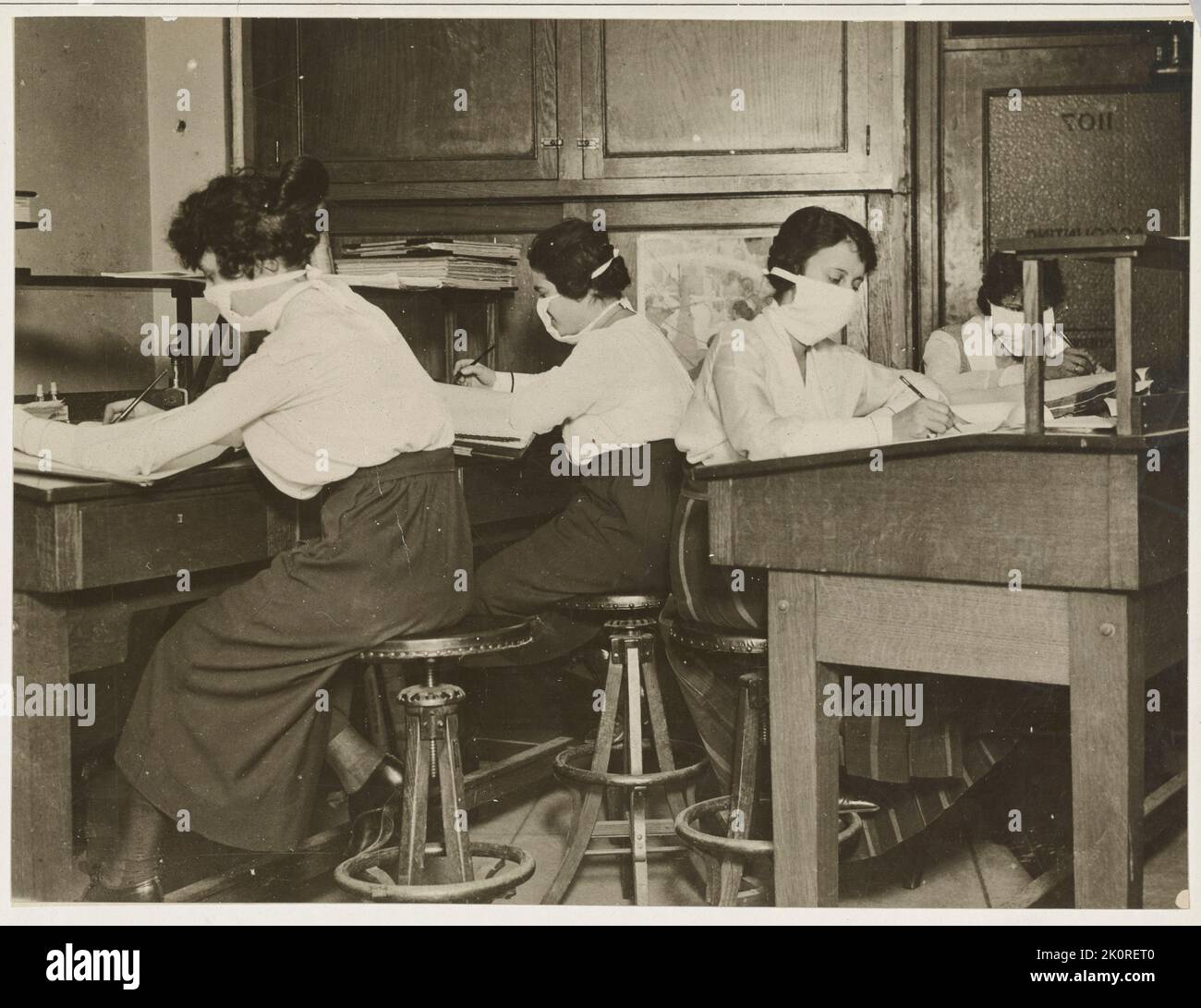 Maschere per la protezione contro l'influenza - gli impiegati femminili al lavoro con maschere attentamente legate intorno ai loro volti durante il 1918 Pandemic, New York, NY,10/16/1918. Foto Stock