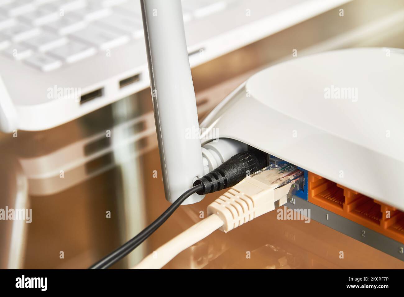 Router wi-fi wireless bianco vicino a un computer portatile su un vetro tabella Foto Stock