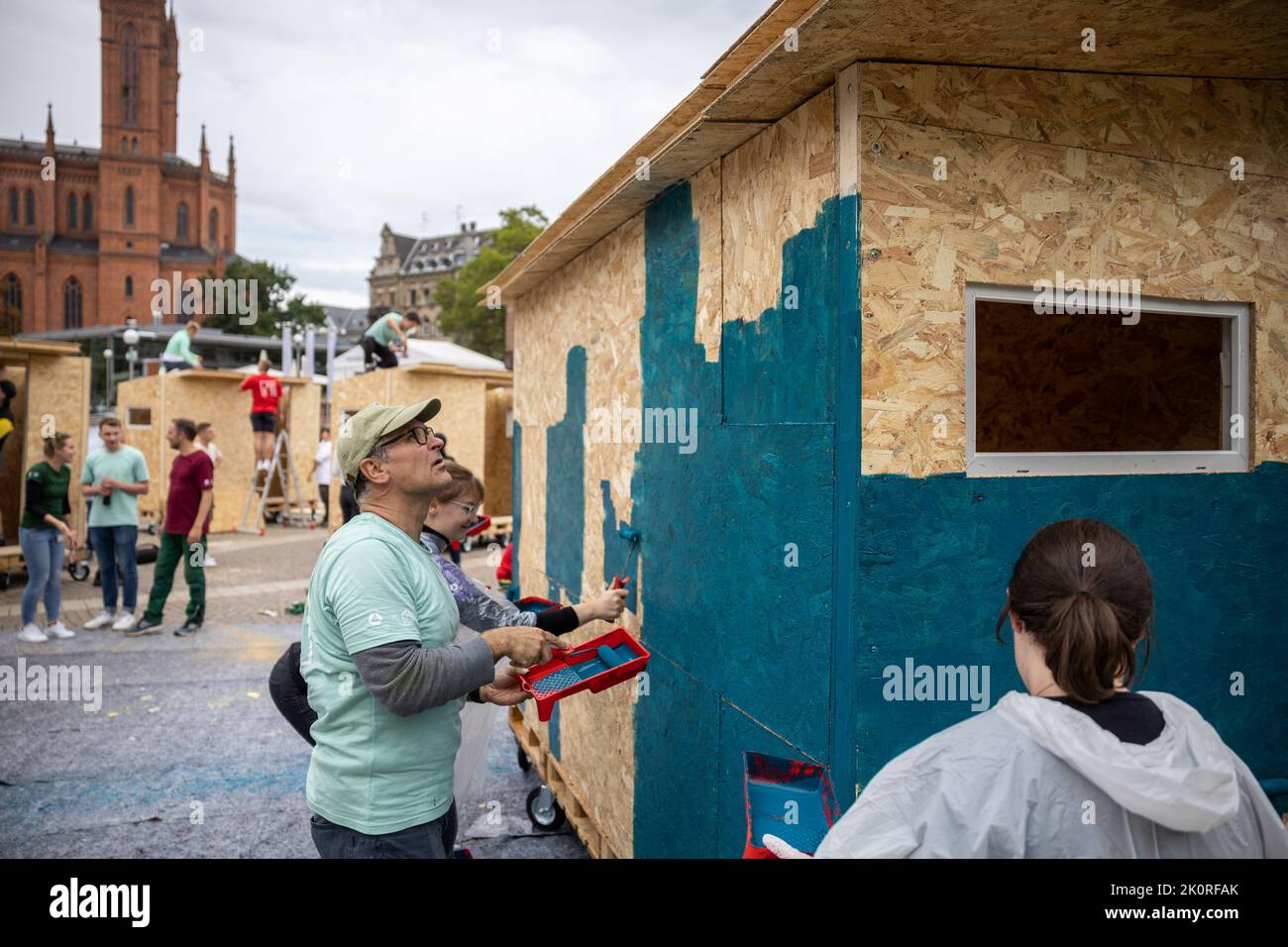 Wiesbaden, Germania. 13th Set, 2022. I partecipanti alla campagna dipingono una 'Little House', con altre 'Little House' sullo sfondo. Costruzione di 'piccole Case' per i senzatetto, 100 dipendenti di Commerz Real, insieme con l'associazione Little Home e.V., costruirà cinque case temporanee per le persone senza una casa permanente nel centro di Wiesbaden. Credit: Hannes P. Albert/dpa/Alamy Live News Foto Stock