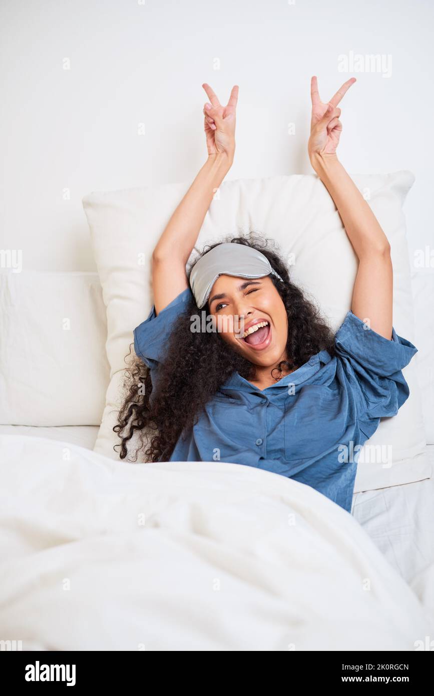 Una bella giovane donna multietnica mostra segni di pace svegliarsi a letto Foto Stock
