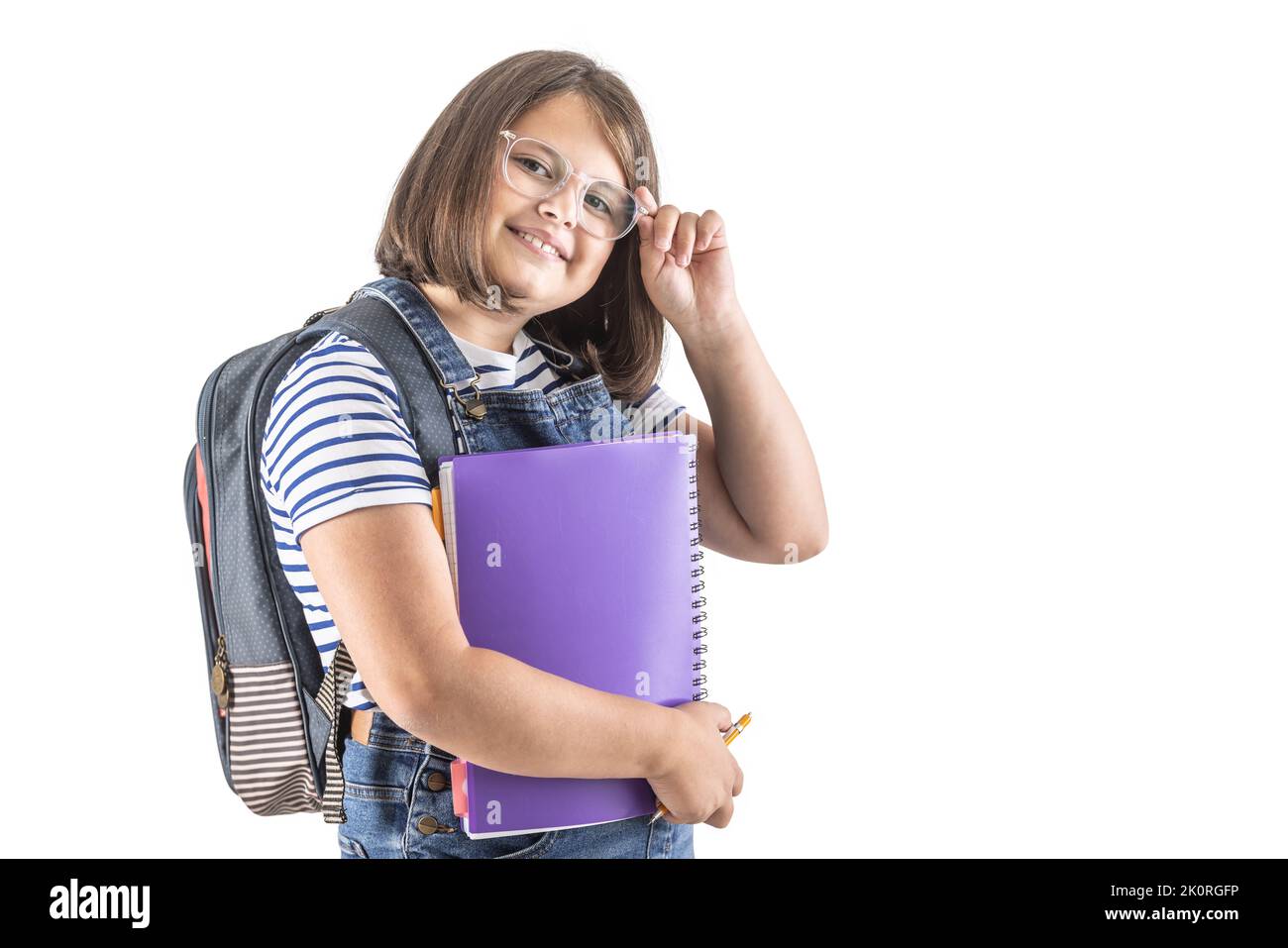 Schoolgirl fissa i suoi occhiali mentre tiene i suoi libri di studio e porta lo zaino. Foto Stock