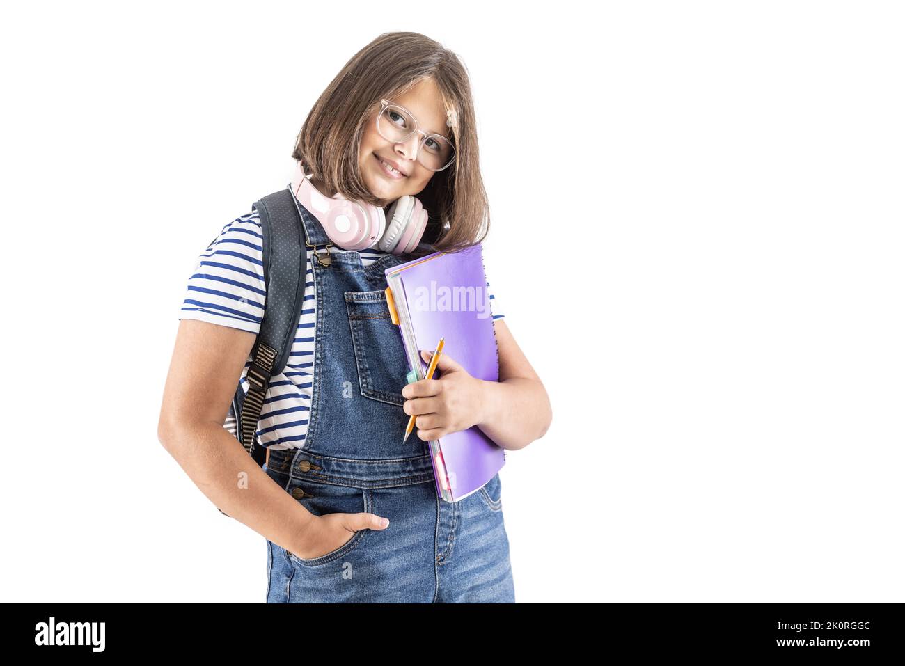 Una studentessa simpatica e sorridente in occhiali con zaino e cuffie può contenere materiali per lo studio e una penna. Foto Stock