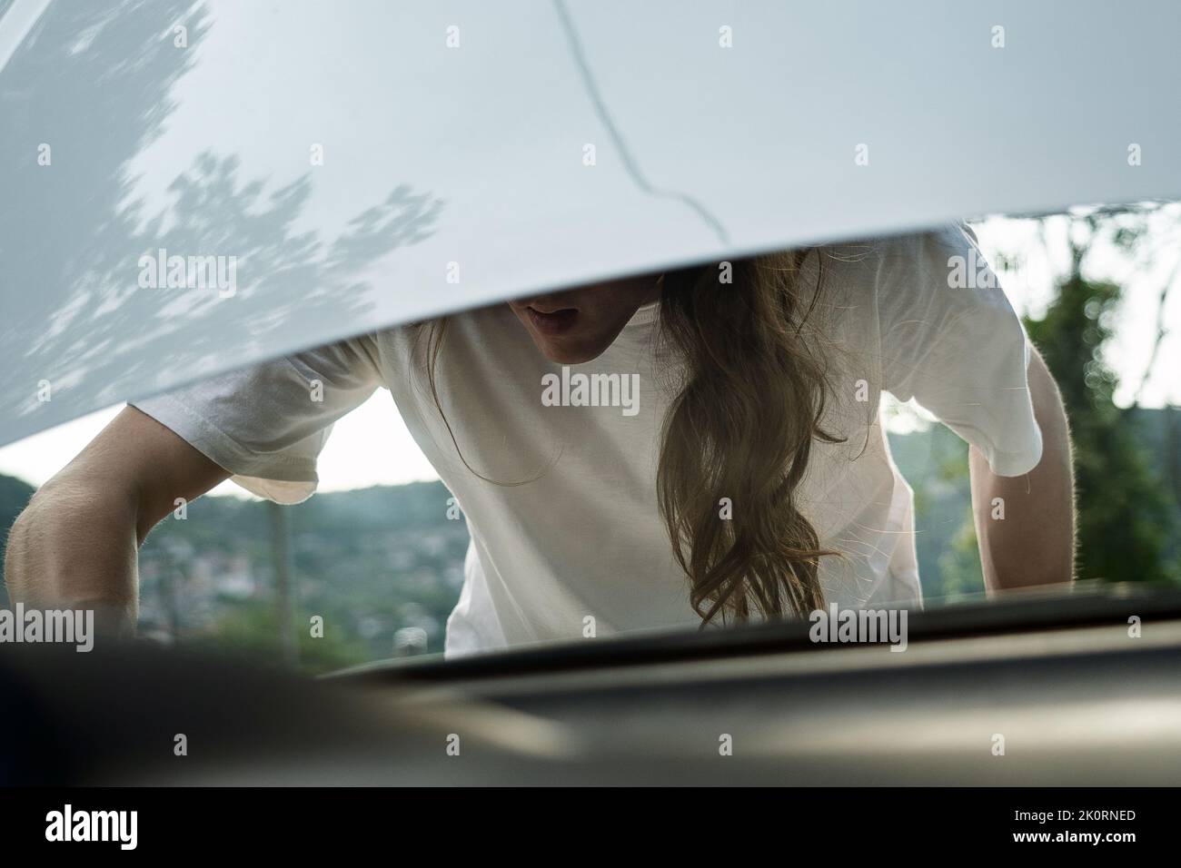 Ragazzo che guarda sotto cofano auto Foto Stock
