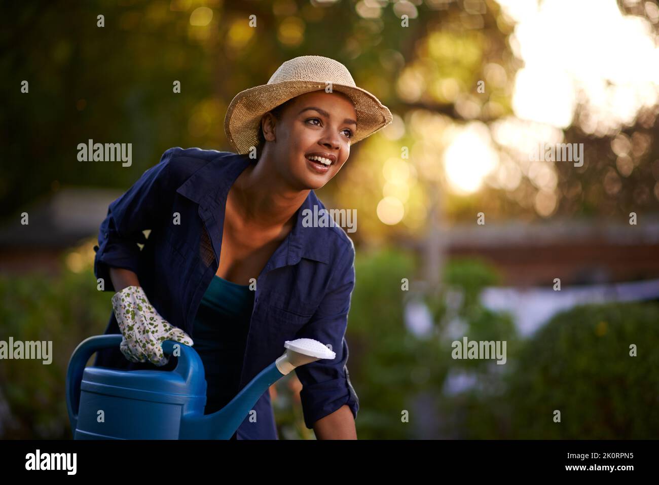 Il mio giardino è il mio posto preferito. Una giovane donna che innaffia il suo giardino. Foto Stock