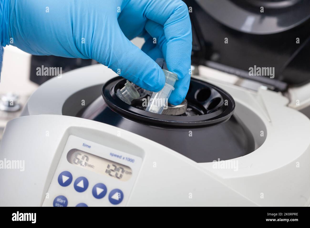 Primo piano di una mano di scienziato che colloca una provetta in una piccola centrifuga da tavolo. Tecnica di purificazione degli acidi nucleici basata su colonna di centrifugazione. Foto Stock