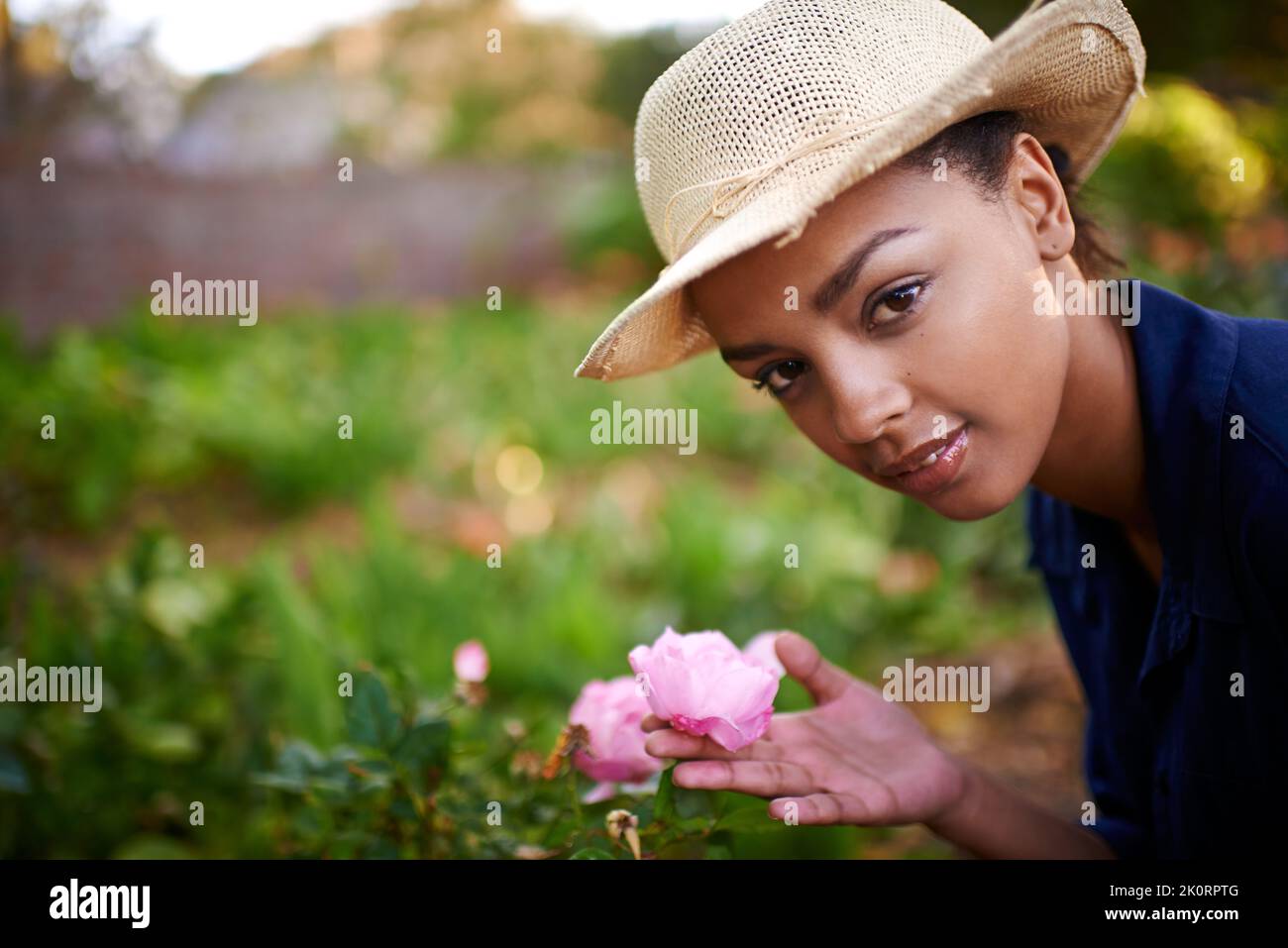 Shes un giardiniere naturale. Ritratto di una giovane donna che ammira le rose nel suo giardino. Foto Stock