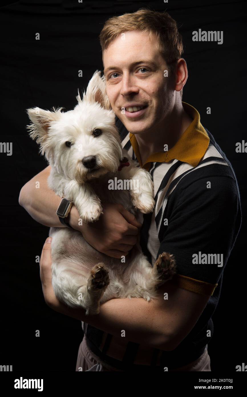 Giovane uomo che tiene il suo West Highland White Terrier Foto Stock