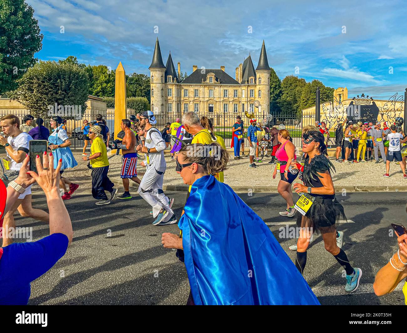 Il peloton colorato di fronte a un ambiente storico. Nel corso della maratona, i partecipanti alla 36th Marathon des Chateaux du Medoc passano un totale di 25 cantine. Spesso passa attraverso il centro del castello e viene offerto vino rosso e acqua Foto Stock