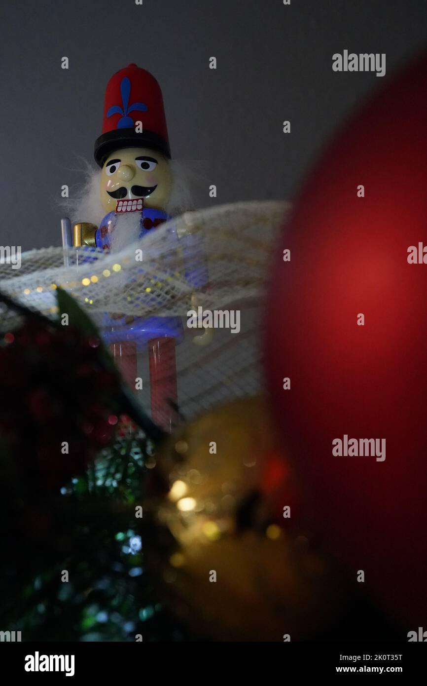 Un tiro a basso angolo di soldato-nutcracker con decorazioni natalizie sotto sullo sfondo scuro Foto Stock