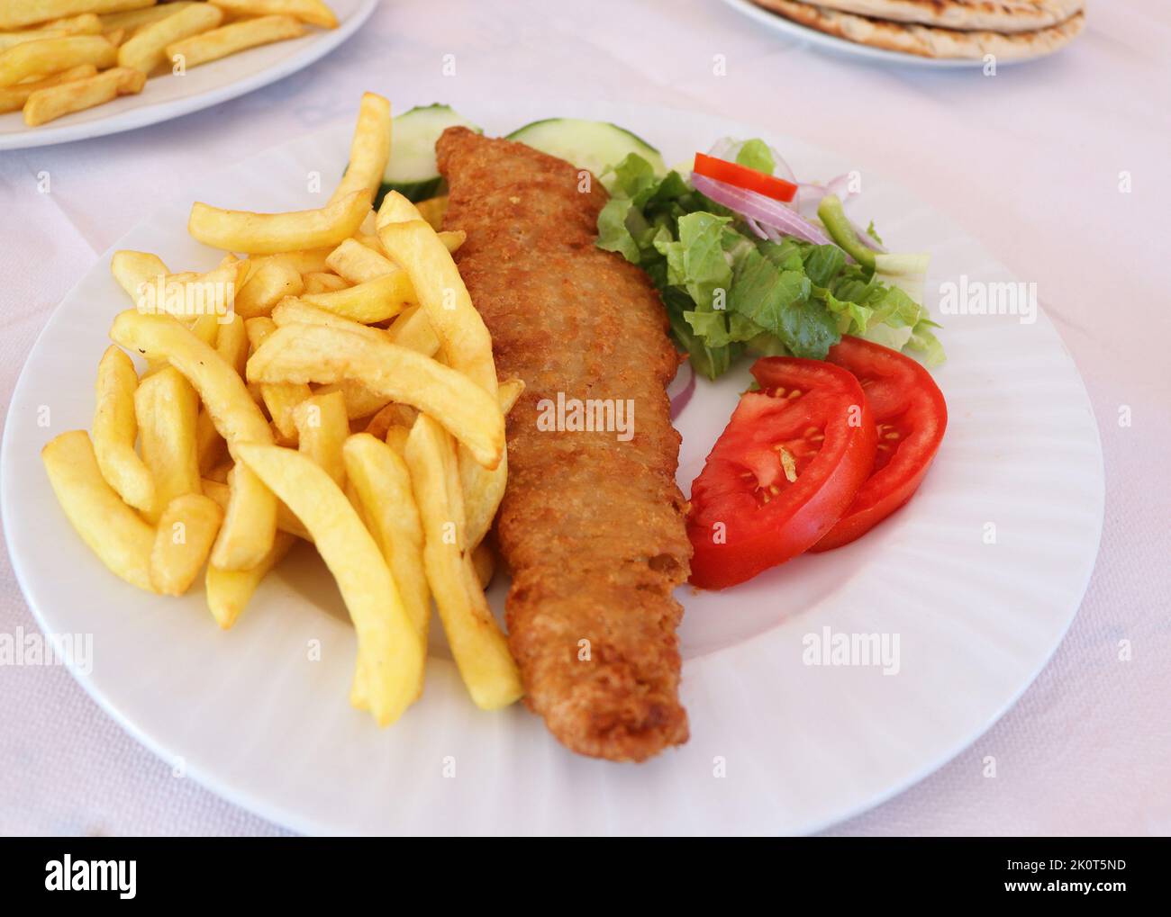 Pesce e patatine fritte. Filetto di pesce fritto con patatine fritte servito su piatto bianco con verdure Foto Stock