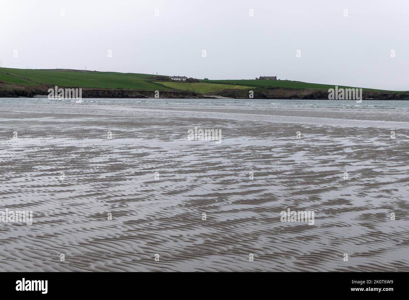 Sabbia ondulata sulla riva di un mare freddo. Paesaggio di mare in una giornata nuvolosa. Splendidi motivi sulla sabbia vicino al corpo d'acqua. Foto Stock