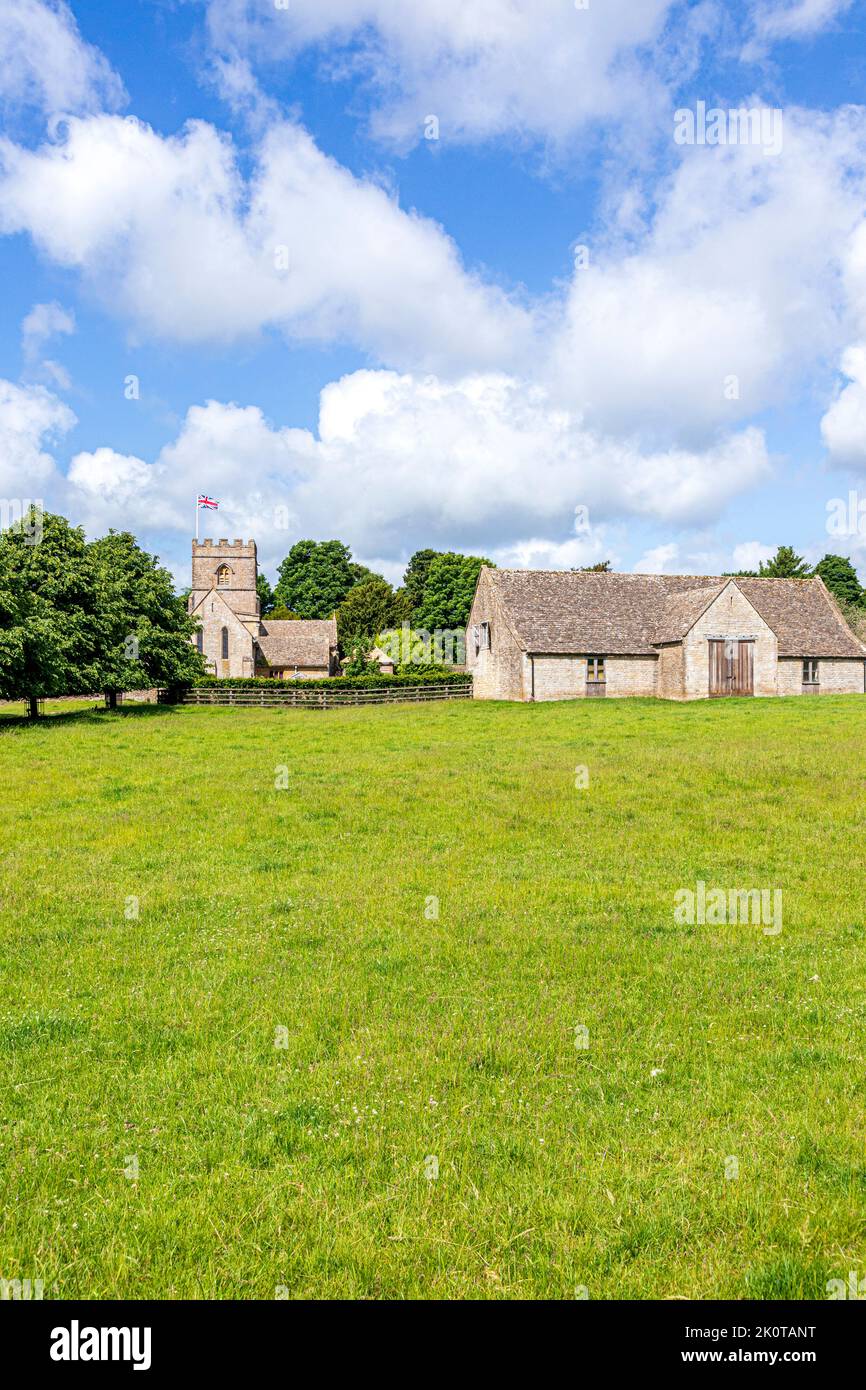 La chiesa normanna di San Michele e tutti gli Angeli e un fienile del 18th ° secolo nel villaggio Cotswold di Guiting Power, Gloucestershire UK Foto Stock