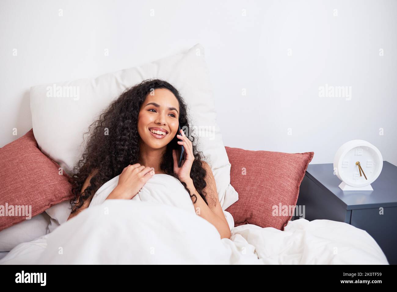Una giovane donna multietnica ride durante la chiamata intima a lunga distanza dal letto Foto Stock