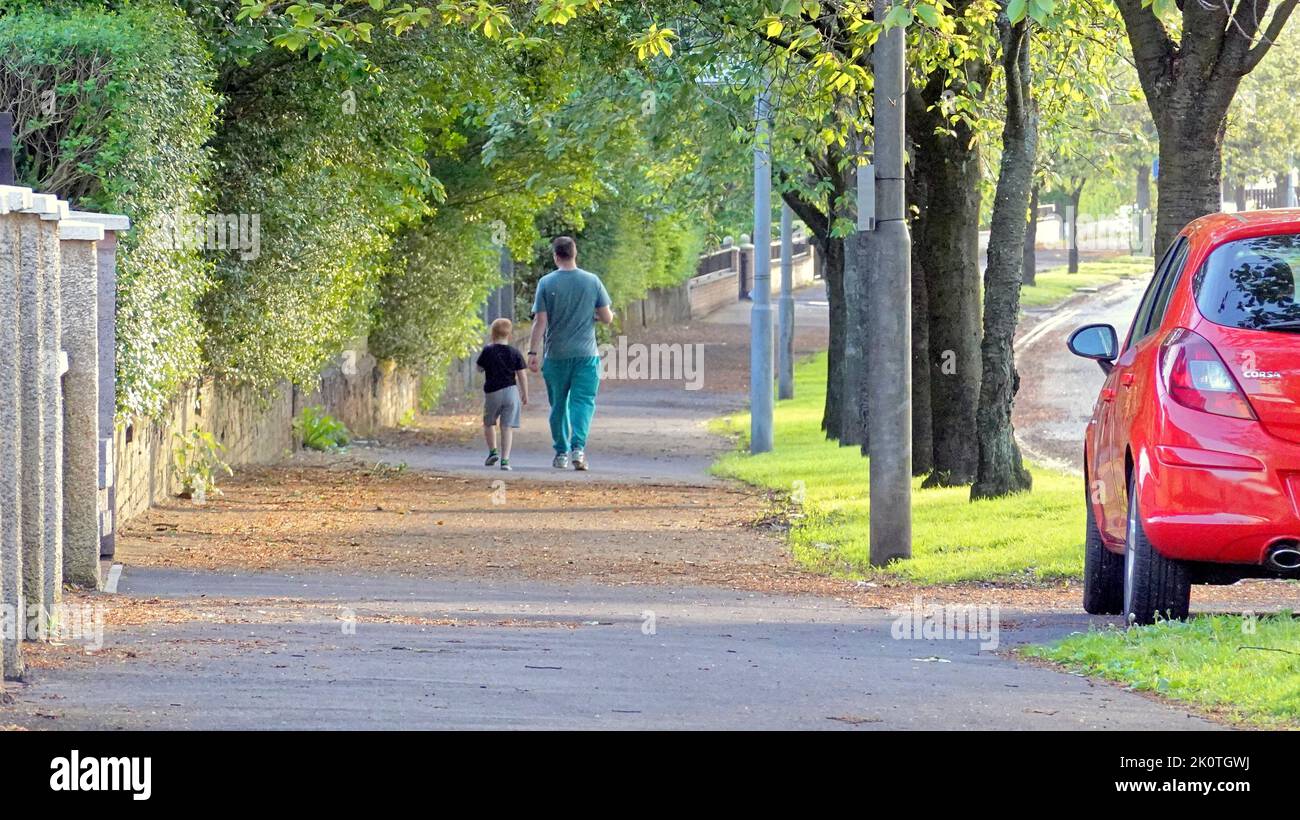 padre e figlio camminano fianco a fianco Glasgow, Scozia, Regno Unito Foto Stock