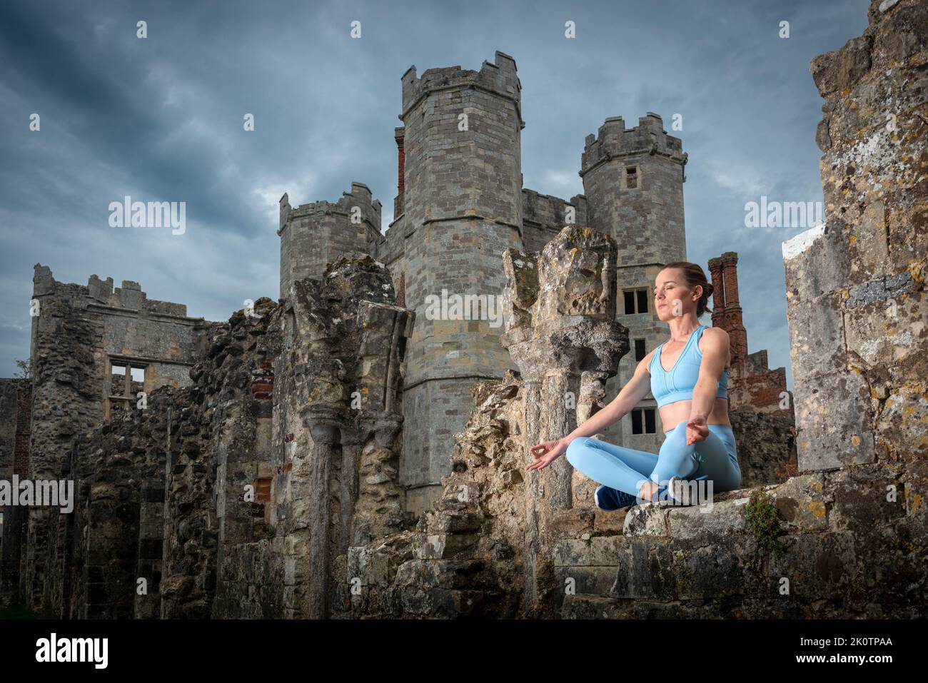 Donna sportiva e in forma che pratica yoga e medita seduto in rovine storiche Foto Stock