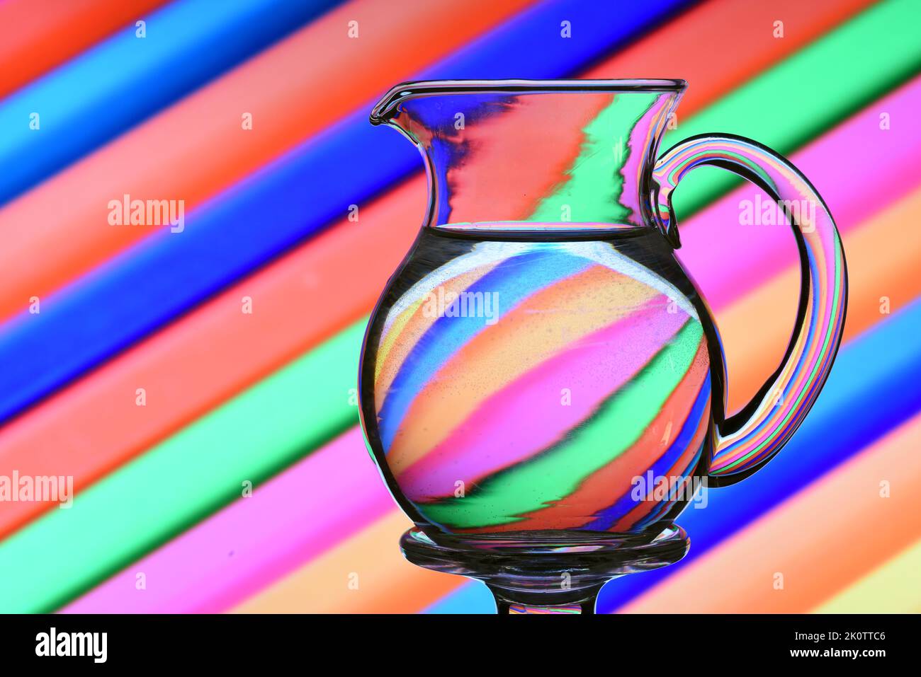 Ilusión óptica creada mediante la refracción de la luz con un beneficiario de cristal lleno de agua y Líneas diagonales de colores Foto Stock