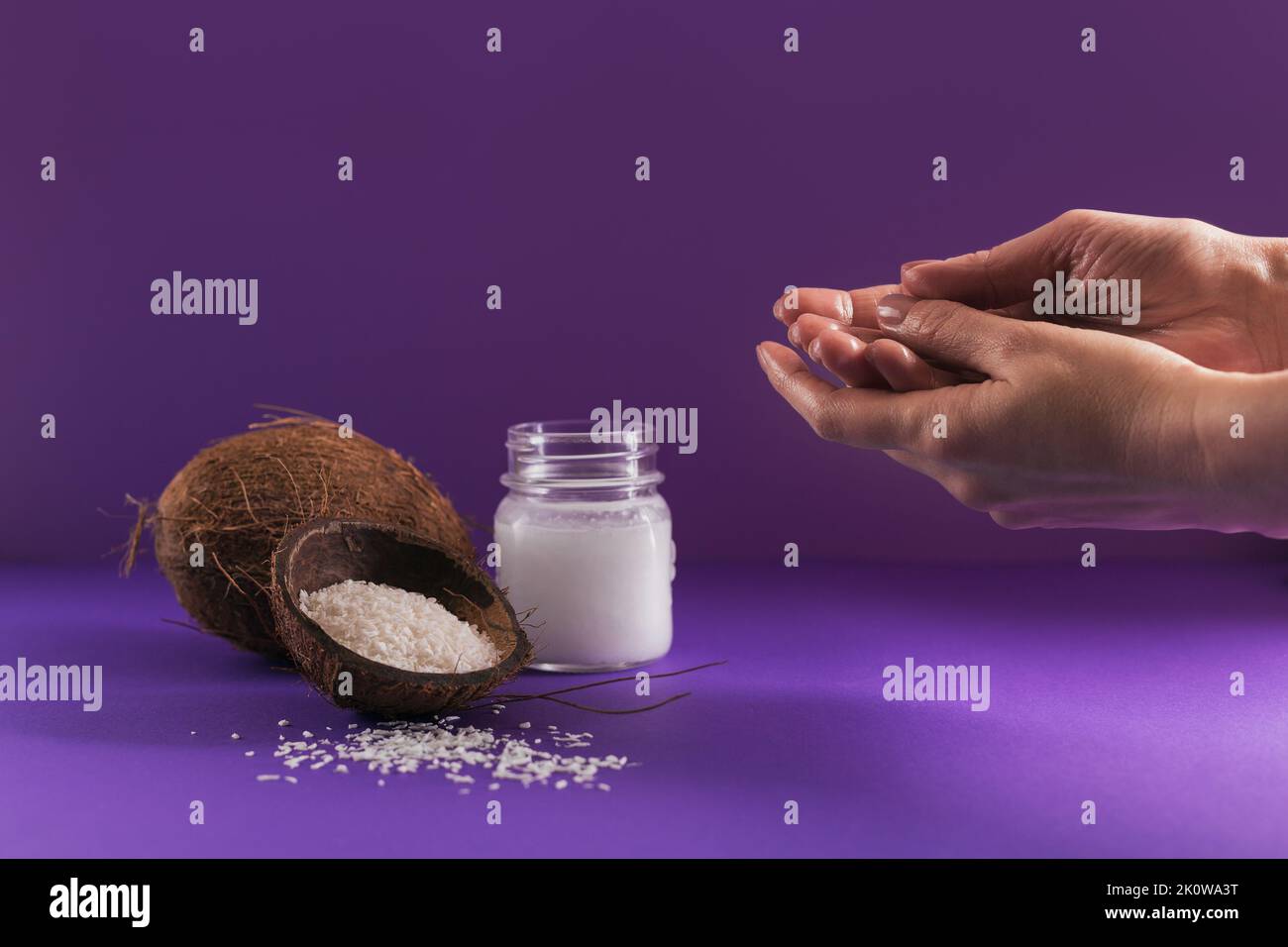 Composizione con crema corpo cosmetica naturale di olio di cocco organico su fondo di colore viola Foto Stock