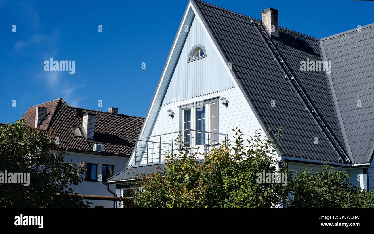 Una casa privata di due piani con tetto triangolare e un'area vicino alla casa contro un cielo blu Foto Stock