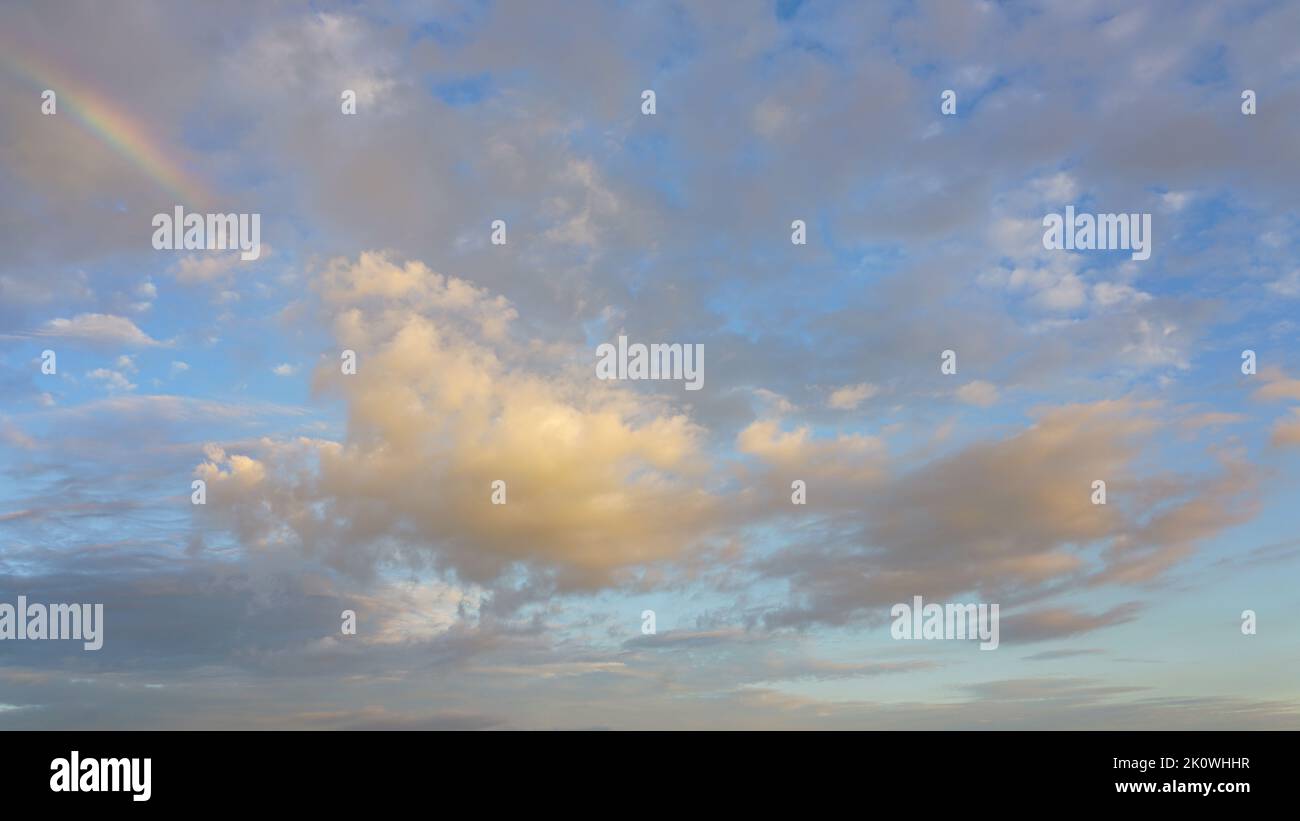 Nel tardo pomeriggio le nuvole di tempesta si infrangono rivelando il cielo blu, le nuvole bianche e l'arcobaleno parziale. Foto Stock