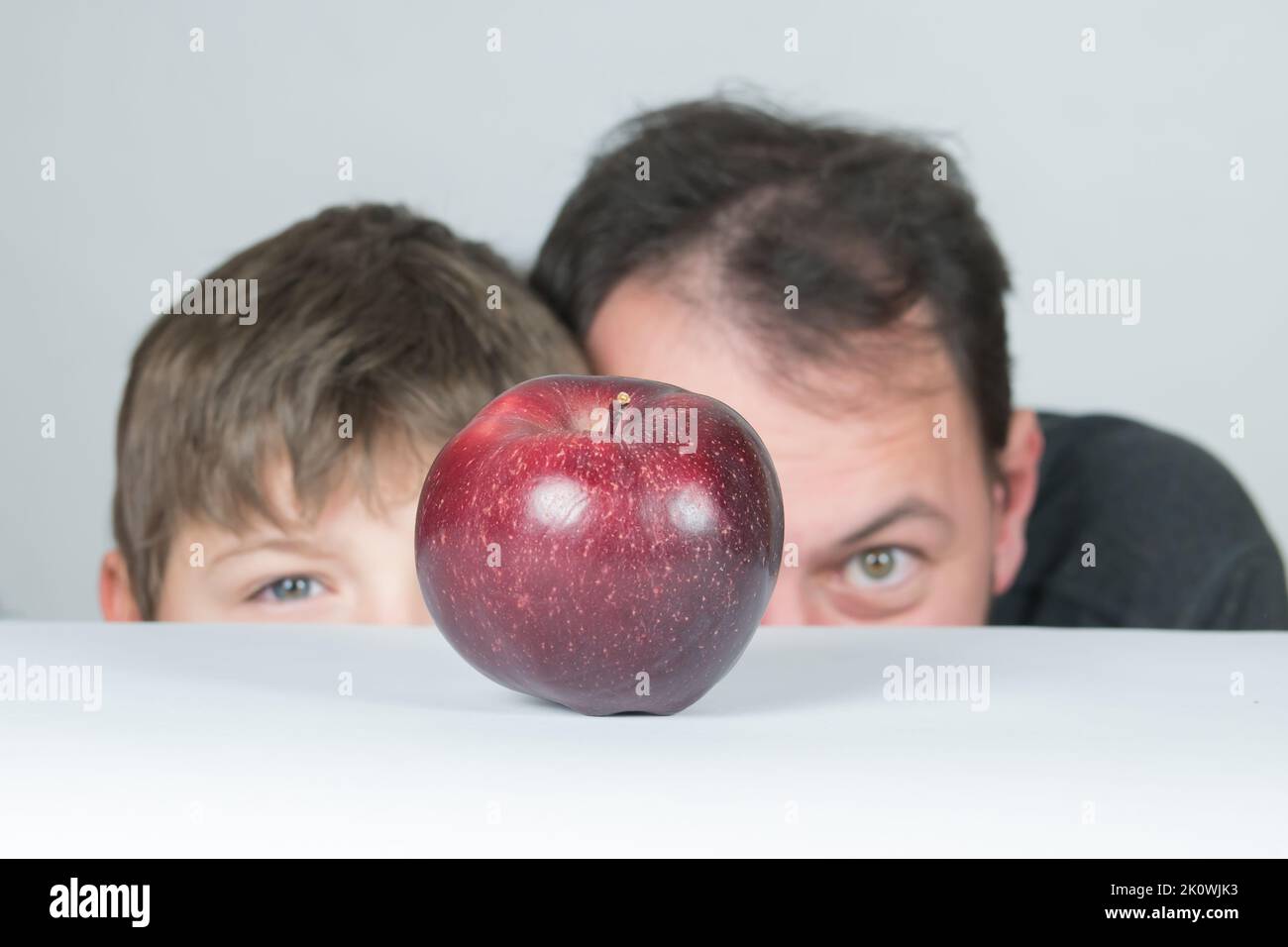 Padre e figlio che guardano alla frutta di mela. Concetto di famiglia vegana. Paternità e infanzia. Momenti insieme a mangiare sano. Momenti felici con la famiglia. Foto Stock