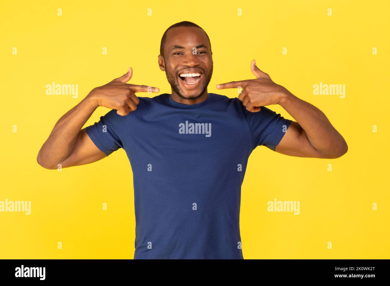 Il ragazzo nero punta le dita contro il sorriso di Toothy su sfondo giallo Foto Stock