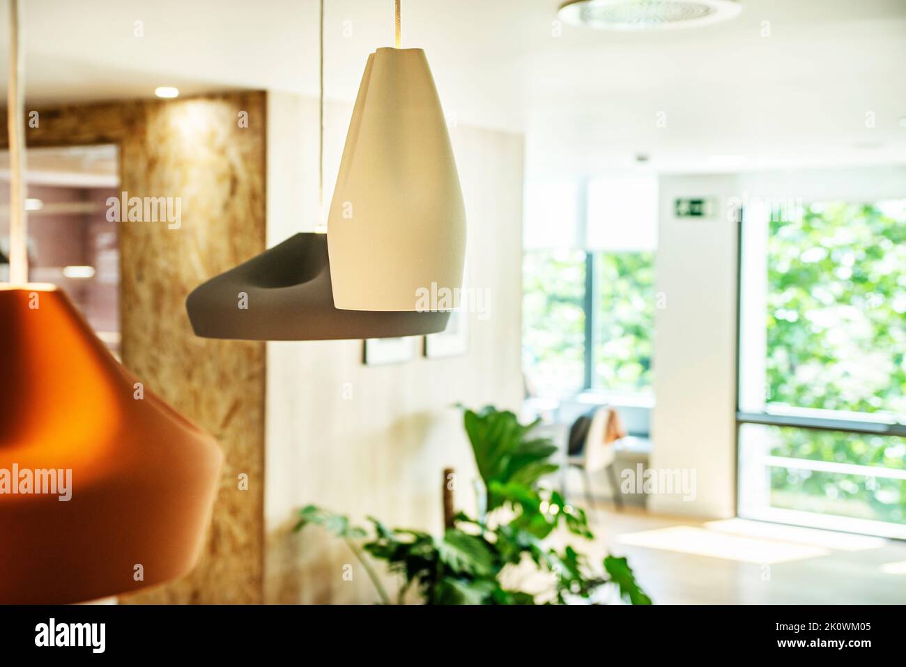Lampade di design appese al soffitto in un ufficio con grandi finestre Foto Stock