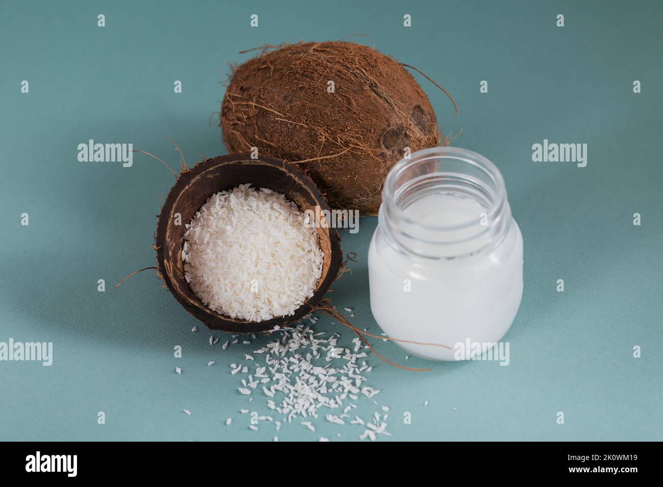 Cocco, fiocchi e olio di cocco in vaso su sfondo blu. Concetto di cucina sana Foto Stock
