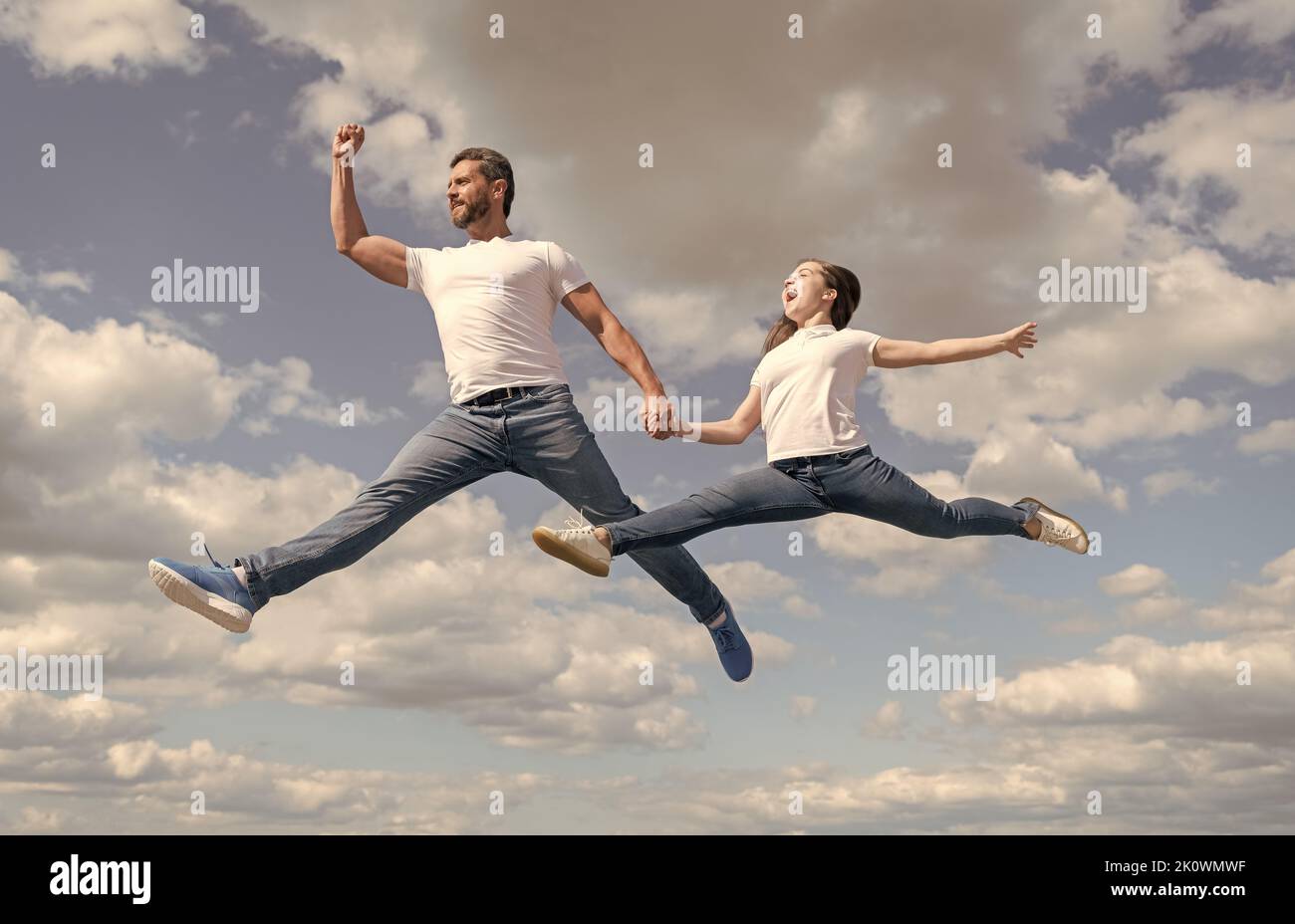 felice famiglia di padre e figlia saltare in cielo Foto Stock